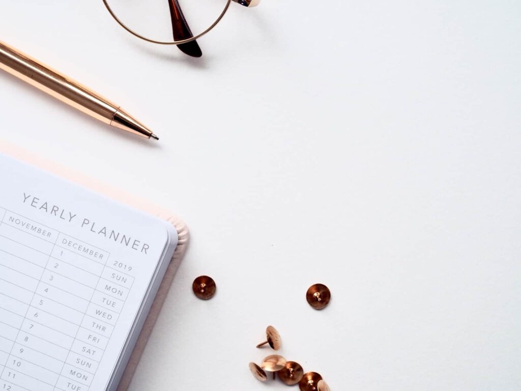 Yearly planner with a pen, thumbtacks, and glasses - update your business plan every year